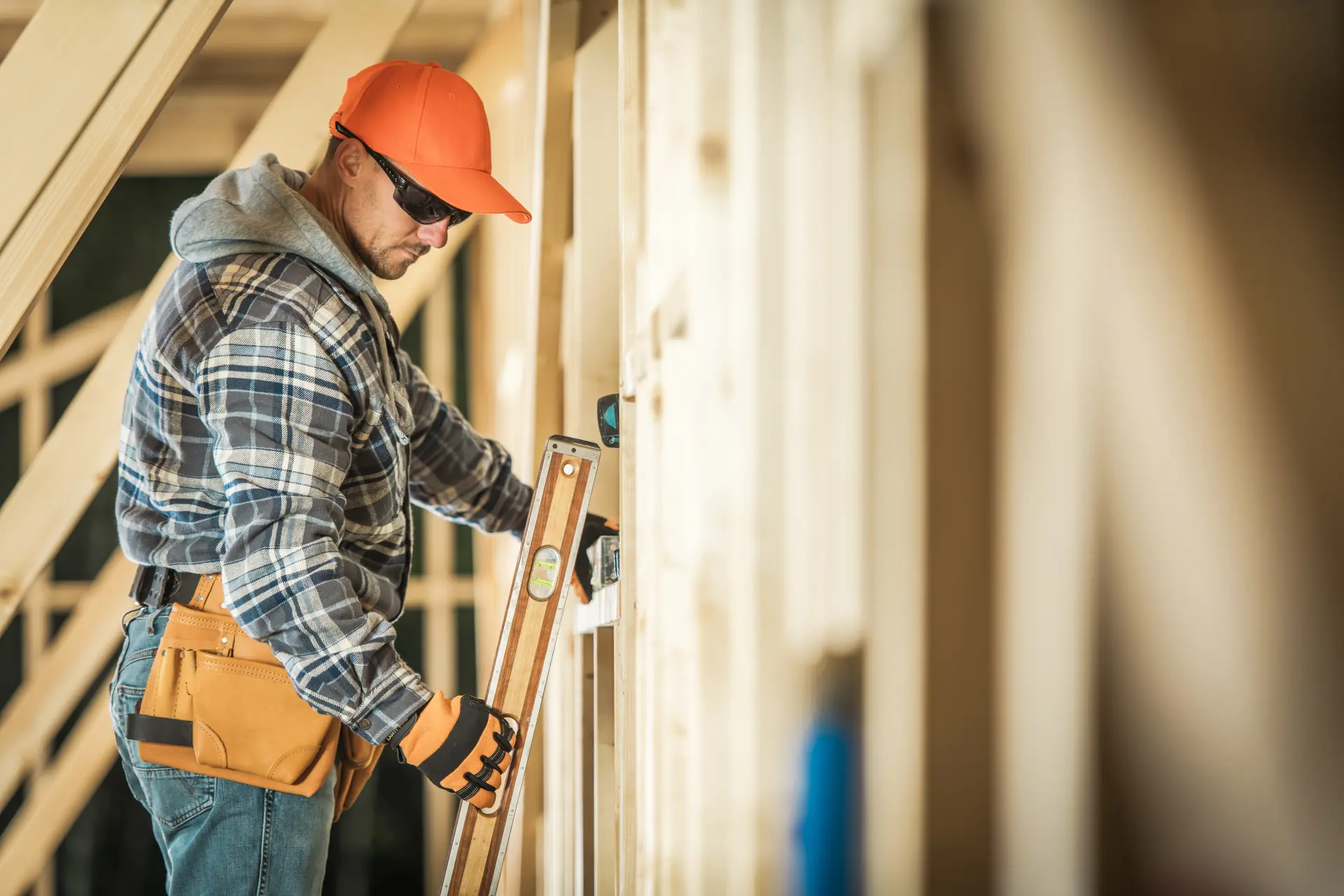 A construction worker putting a level against a stud while framing a new house.